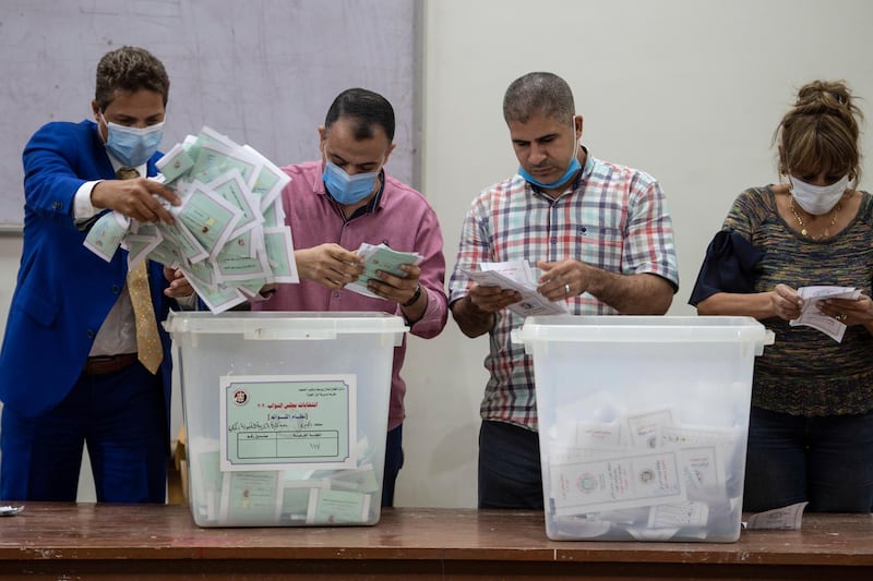 Election officials wearing face masks count ballots following the first round of Egypt's parliamentary elections in Giza. EPA