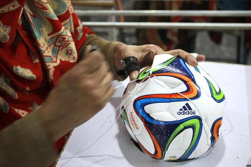 An employee hand-stitches the panels of an Adidas AG "Brazuca Replica Glider" football on the production line at the Forward Sports Ltd factory in Sialkot, Punjab. Asad Zaidi / Bloomberg

