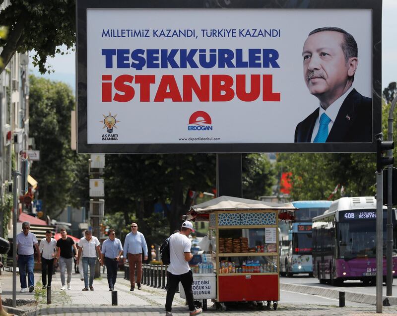 People walk past a poster for Turkey's President Tayyip Erdogan in Istanbul, Turkey, June 25, 2018. The poster reads: "Our people won, Turkey won, Thank you istanbul". REUTERS/Osman Orsal