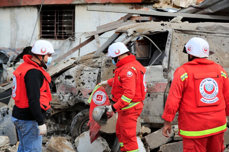 Paramedics collect equipment from the wreckage of a vehicle after the strikes. AP 