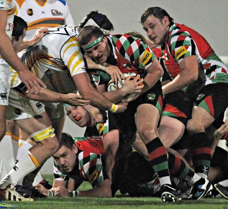 Abu Dhabi Harlequins player Mike Ballard (in green head tape) tries to reach the try line against the Dubai Hurricanes in Dubai this year. He suffered spinal damage in a match this month.  Jeff Topping for The National 