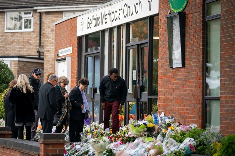 The Rev Clifford Newman, fourth left, talks with Julia Amess, the widow of Conservative MP David Amess, as friends and family members view flowers and tributes outside Belfairs Methodist Church in Essex. AP.