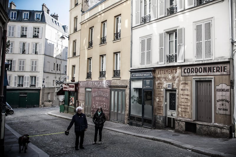 People walk their dog on a deserted street transformed into a movie set, in Paris, France. The shooting of a cinema film taking place in the 1940s in the Montmartre district was interrupted and its sets left in place as France is under lockdown. EPA