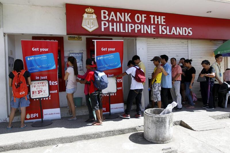Filipinos line up at an ATM in Roxas City, Capiz province, Philippines. According to the national disaster relief agency, more than 3 million people have been displaced by Typhoon Haiyan, which struck November, 8 flattening cities and towns in the eastern Philippines and killing at least 3,637 people.  Bagus Indahono/EPA