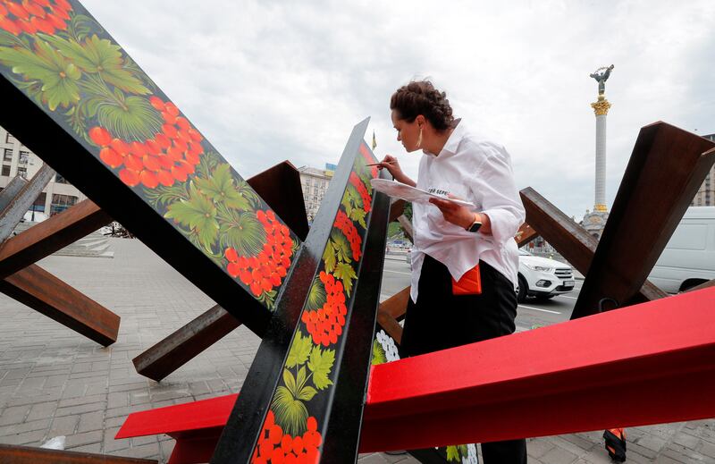 Street artist Varvara Logvyn paints national emblems on to anti-tank obstacles in Independence Square in Kyiv, Ukraine. EPA