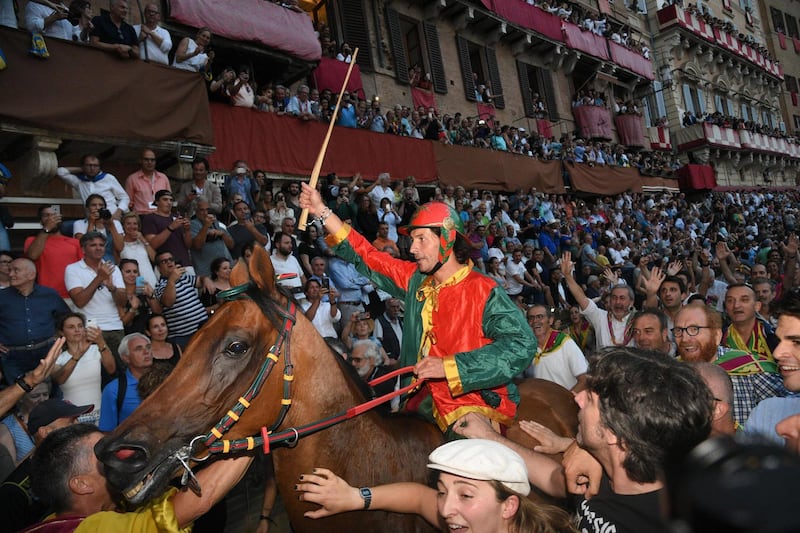 The winning jockey waves his whip to the crowd. Claudio Giovanni / EPA