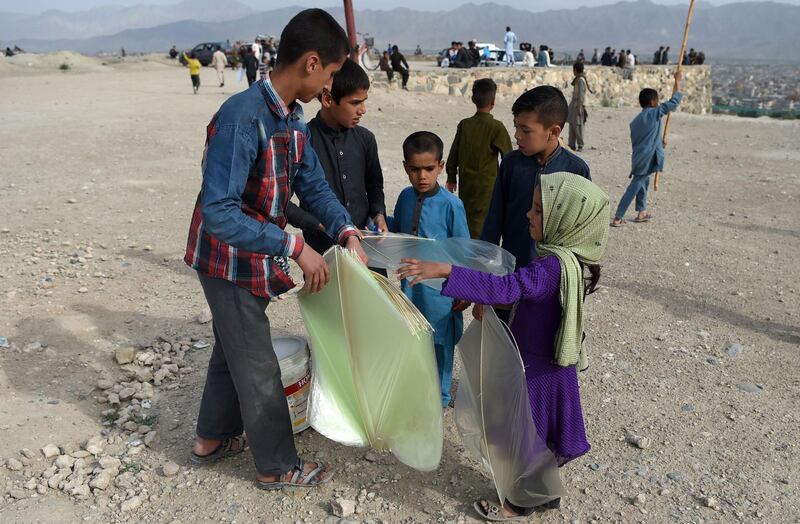 A young kite vendor, right, sells plastic kites to children.