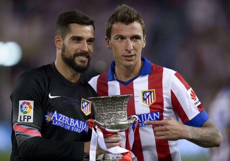 Atletico Madrid goalkeeper Angel Moya and forward Mario Mandzukic pose with the Supercopa de Espana trophy after winning it on Friday over Real Madrid. Dani Pozo / AFP