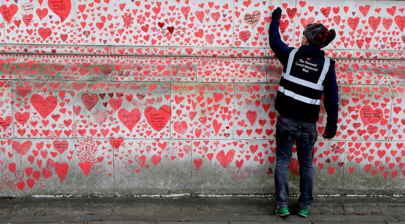 A man paints red hearts onto the Covid-19 Memorial Wall on the Embankment in London. AP Photo