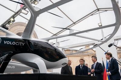 French President Emmanuel Macron, second left, views a VoloCity aircraft with Dirk Hoke, to his right. 