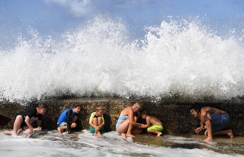 Locals shelter behind a sea wall as large waves generated by cyclone Oma crash onto it at Snapper Rocks on the Gold Coast, Queensland, Australia. EPA