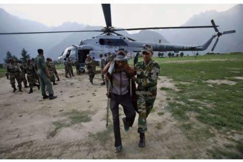 An Indian army soldier helps evacuate a man from the upper reaches of mountains in Joshimath, India. Tens of thousands of people are in need of assistance after heavy monsoon rains in India's north.