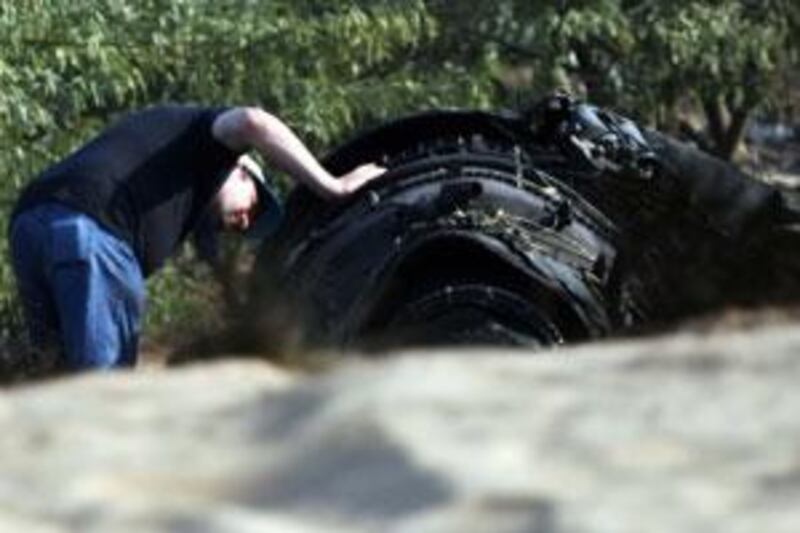 An investigator examines an engine at the site of the crash.