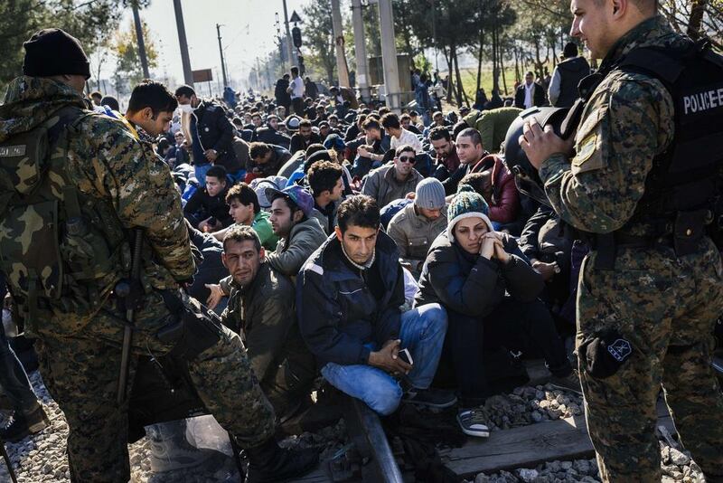 Macedonian police officers stand guard as migrants from Liberia, Morocco, Pakistan, Sri Lanka and Sudan block railway tracks near Gevgelija on the Greek-Macedonian border on November 19, 2015. Macedonia, Slovenia, Serbia and Croatia closed their borders on Friday to those not coming from war-torn countries. Dimitar Dilkoff/AFP Photo

