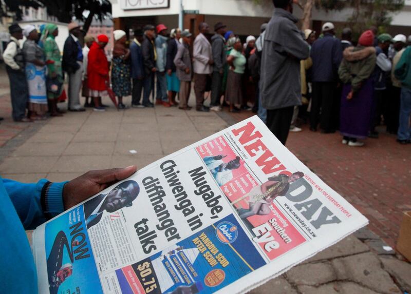 A man reads a newspaper as residents queue to draw money at a bank in Harare, Zimbabwe, November 17, 2017. REUTERS/Philimon Bulawayo