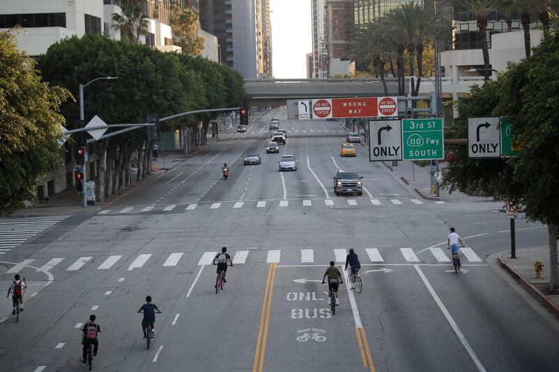 A group of cyclists take advantage of the light traffic along Figueroa Street on Wednesday, April 1, 2020, in Los Angeles. The spread of the coronavirus statewide has, so far, been slow enough to give the state time to prepare for an expected spike in cases. (AP Photo/Marcio Jose Sanchez)