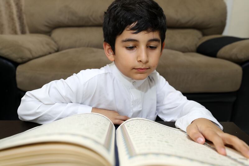 Rayan, on his first fast, reads the Quran. He was keen to join the Ramadan traditions. Chris Whiteoak / The National