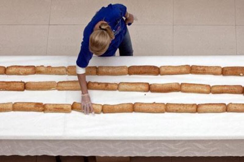 Dubai, October 7, 2010 - A volunteer straightens a section of the world's longest sandwich made at Dubai Outlet Mall in Dubai, October 7, 2010. Liz Smith of Guinness World Records oversaw the measuring of the sandwich and later verified it being 2,667.13 meters long. The sandwich sections will be distributed to laborers in three different camps and some families in Dubai. (Jeff Topping/The National) 