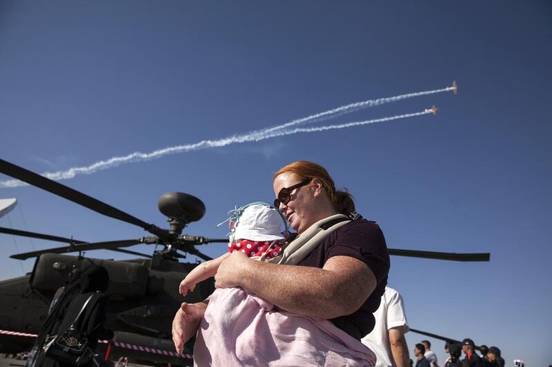 Tracy Bray checks on her 6-month-old daughter Matilda, who is wearing a double layer of ear protection, as they walk past a helicopter on display alongside other UAE military aviation machinery at the10th Annual Al Ain Aerobatics Show. Silvia Razgova / The National