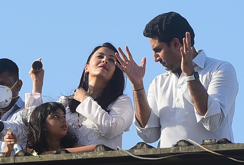 Bollywood actors Abhishek Bachchan (R) and Aishwarya Rai Bachchan along with their daughter Aaradhya clap from atop a residential building to thank essential service providers during a one-day Janata (civil) curfew imposed amid concerns over the spread of the COVID-19 novel coronavirus, in Mumbai on March 22, 2020.  / AFP / Sujit Jaiswal
