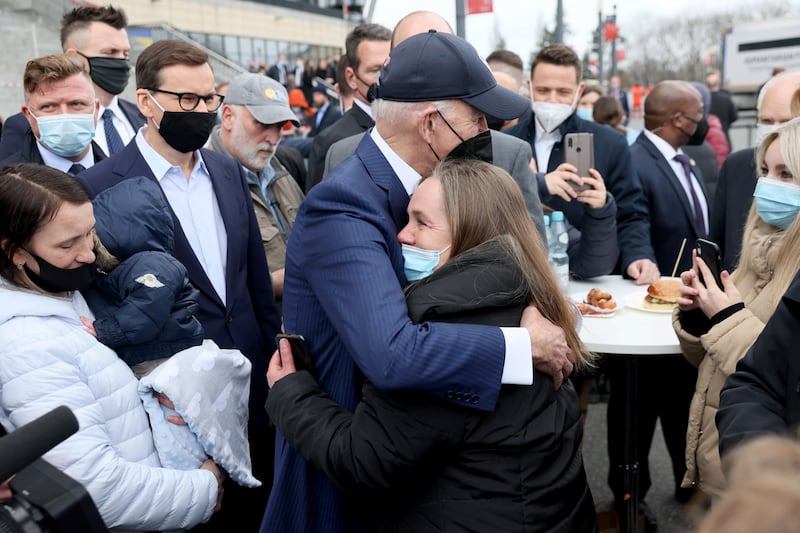 Mr Biden, flanked by the mayor of Warsaw Rafal Trzaskowski and Polish Prime Minister Mateusz Morawiecki, hugs a woman as he visits Ukrainian refugees. Reuters