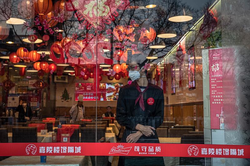 epa08202431 A waiter wearing a protective face mask waits for customers at a restaurant in Beijing, China, 08 February 2020. The novel coronavirus (2019-nCoV), which originated in the Chinese city of Wuhan, has so far killed at least 724 people and infected over 34,000 others, mostly in China.  EPA/ROMAN PILIPEY
