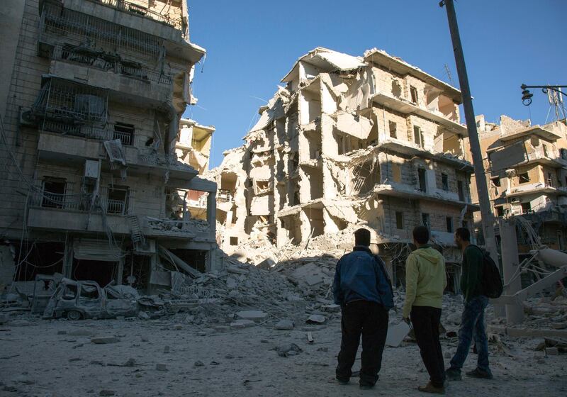 Syrian men look at a heavily damaged building following air strikes on rebel-held eastern areas of Aleppo on September 24, 2016. - Heavy Syrian and Russian air strikes on rebel-held eastern areas of Aleppo city killed at least 25 civilians on Saturday, the Britain-based Syrian Observatory for Human Rights said, overwhelming doctors and rescue workers. (Photo by KARAM AL-MASRI / AFP)