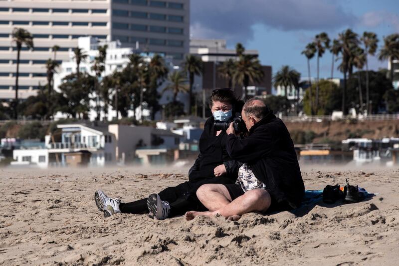 A couple sits on a beach amid the coronavirus pandemic in Santa Monica, California on March 18, 2020. EPA