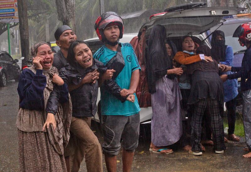 People react as the body of a relative is recovered from the rubble of a building at an area affected by an earthquake in Mamuju, West Sulawesi, Indonesia. A strong, shallow earthquake shook Indonesia's Sulawesi island just after midnight Friday, toppling homes and buildings, triggering landslides. AP Photo