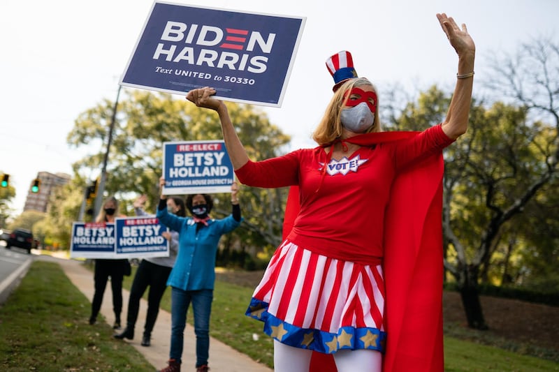 A person dressed in a 'Vote' superhero costume holds a campaign sign for Joe Biden outside a polling location in Atlanta, Georgia. Bloomberg