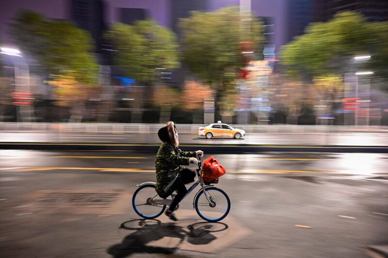 A person wearing a protective facemask rides a bicycle along a street in Wuhan on January 26, 2020, a city at the epicentre of a viral outbreak that has killed at least 56 people and infected nearly 2,000. China on January 26 expanded drastic travel restrictions to contain an epidemic that has killed 56 people and infected nearly 2,000, as the United States, France and Japan prepared to evacuate their citizens from a quarantined city at the outbreak's epicentre. / AFP / Hector RETAMAL
