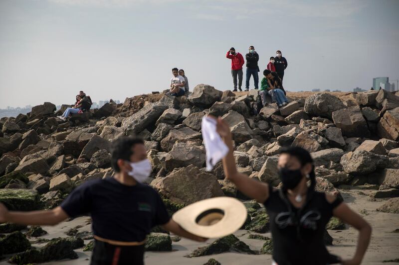 People look at Frank Valdivia and Rocio Pereyra dance Marinera, a typical dance from the Peruvian coast, on the beach in the Chorrillos district of Lima, Peru. AP Photo