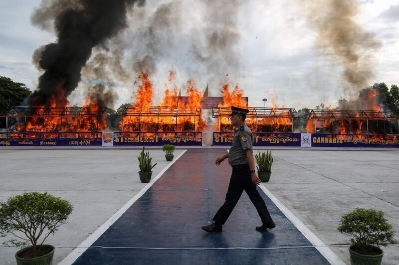 A police officer walks in front of a burning pile of seized illegal drugs during a destruction ceremony to mark the United Nations' "International Day against Drug Abuse and Illicit Trafficking" in Yangon, Myanmar.  AFP