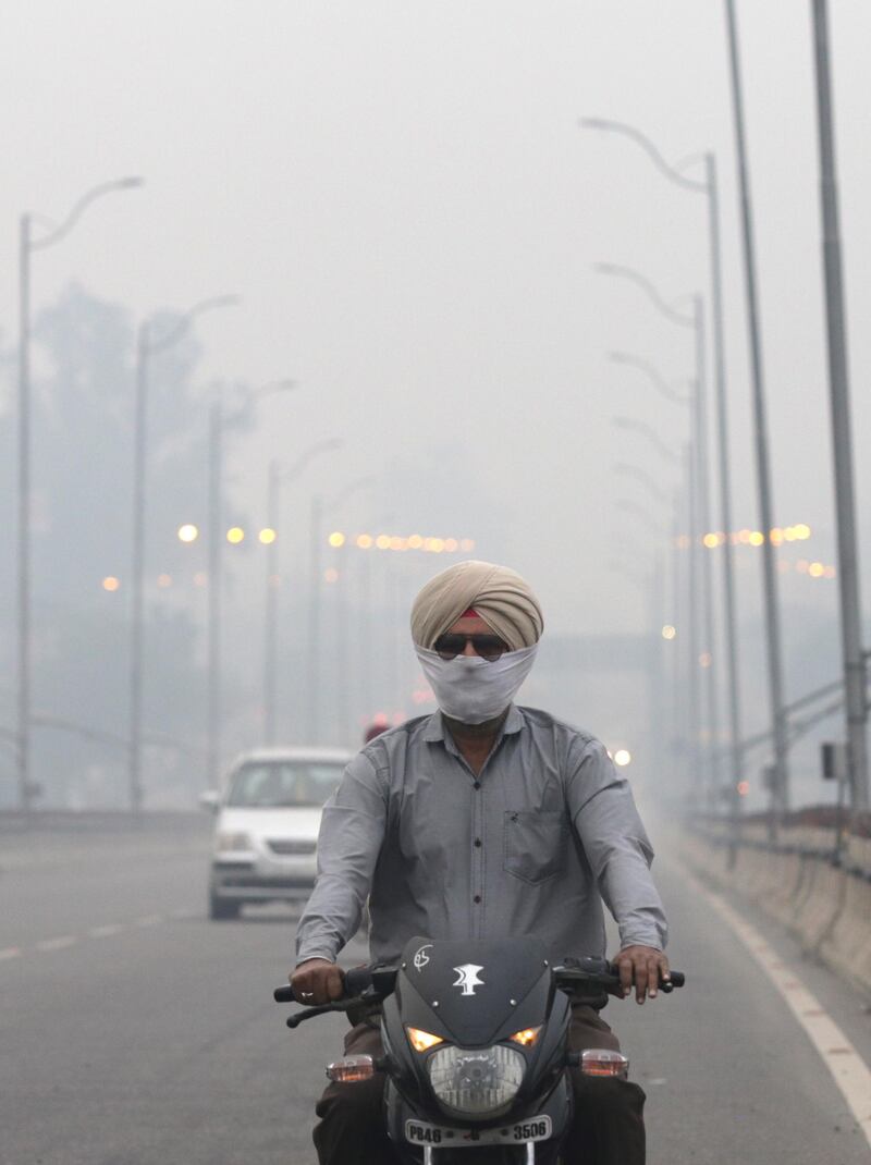 An Indian commuter rides with his face covered on a road engulfed in haze in Amritsar, India.  EPA