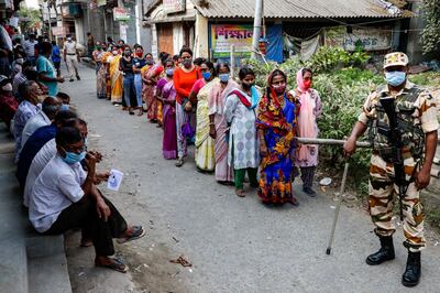 An Indian paramilitary soldier stands vigil around a polling booth as voters  wait to cast their votes during the fifth phase of West Bengal state elections in Newtown Rajarhat, North 24 Parganas district, India, Saturday, April 17, 2021. (AP Photo/Bikas Das)