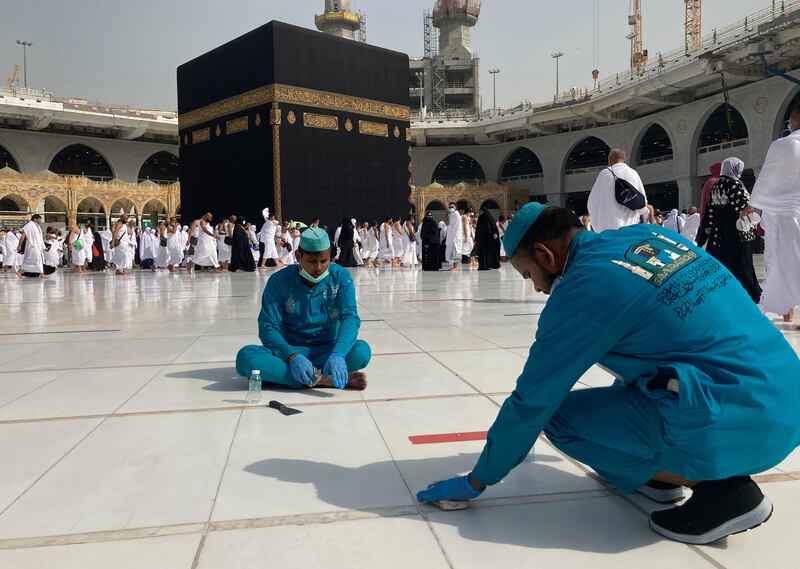 Workers remove social-distancing signs at the Grand Mosque in the Muslim holy city of Mecca, Saudi Arabia.   AP Photo