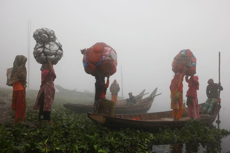 Women carry plastic and aluminium utensils to sell on a foggy morning in Dhaka, Bangladesh. Reuters