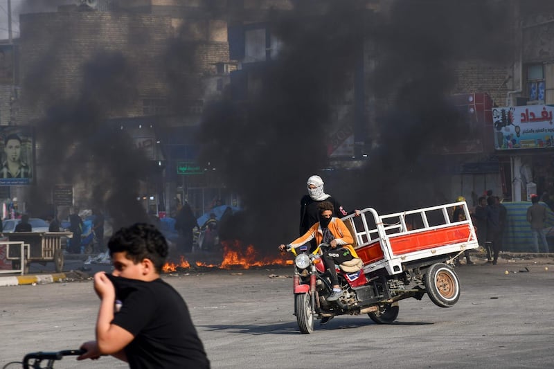 Iraqi protesters run for cover during clashes with police during anti-government demonstrations in the city of Nasiriyah in the Dhi Qar province in southern Iraq.  AFP