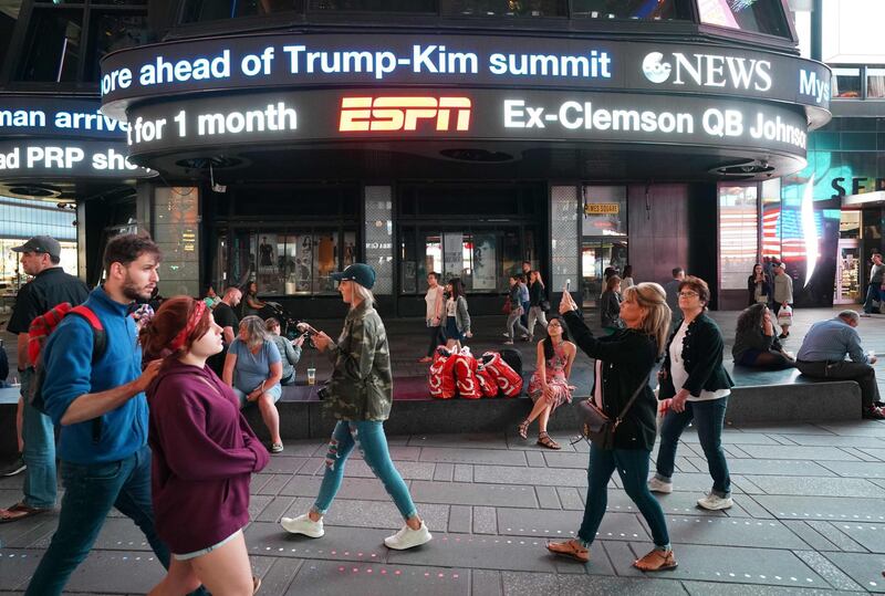 People in Times Square walk past the ABC TV studios as news of the US-North Korea summit ticks past in New York. Don Emmert / AFP