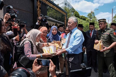 Malaysia’s King Sultan Abdullah Sultan Ahmad Shah (centre R) hands out packages of fast food to reporters standing outside the National Palace in Kuala Lumpur on February 25, 2020. Intense political jockeying is underway to form a new government in Malaysia after Mahathir Mohamad, the world's oldest leader, resigned then was appointed interim leader. / AFP / Syaiful Redzuan
