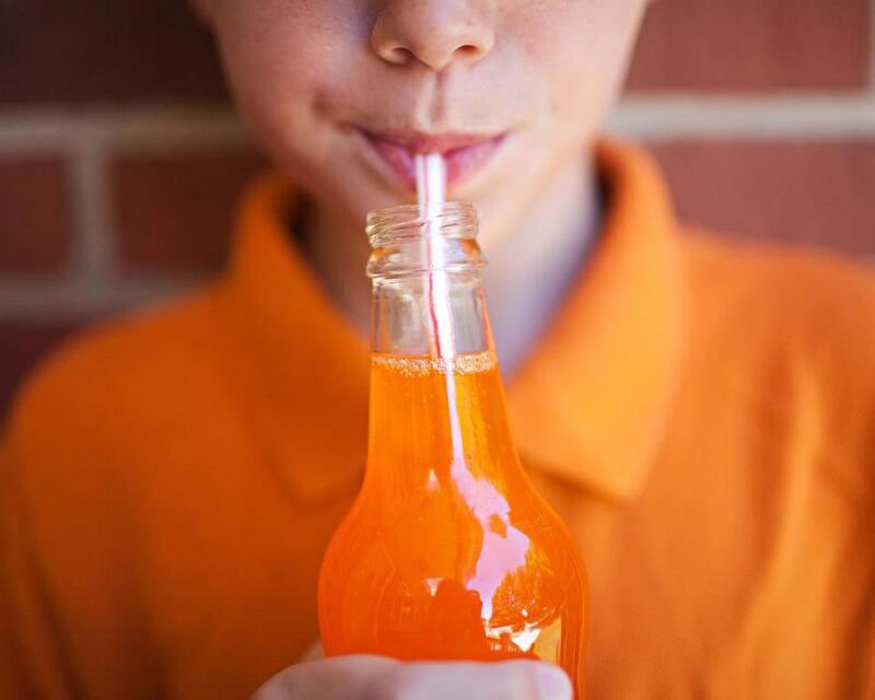 Boy drinking orange soda. The Cancer Research UK has urged the British government to improve children’s diets after research showed those between the ages of 11 and 18 drank about one bathtub full of sugary drinks a year. Getty Images