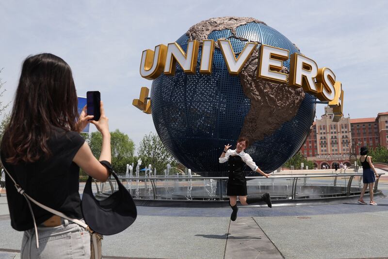 A tourist in front of a sign of the Universal Resort, at the Universal Studios theme park, as it reopens to the general public. Reuters