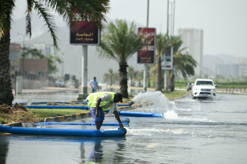 Municipality workers drain water from a flooded road in Fujairah. Khushnum Bhandari / The National
