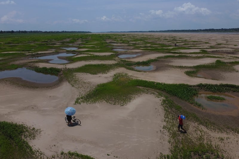 Residents of a riverside community in Amazonas state, Brazil, carry food and containers of drinking water distributed by the state's humanitarian aid action, amid a continuing drought and high temperatures that affect the region of the Solimoes River. AP