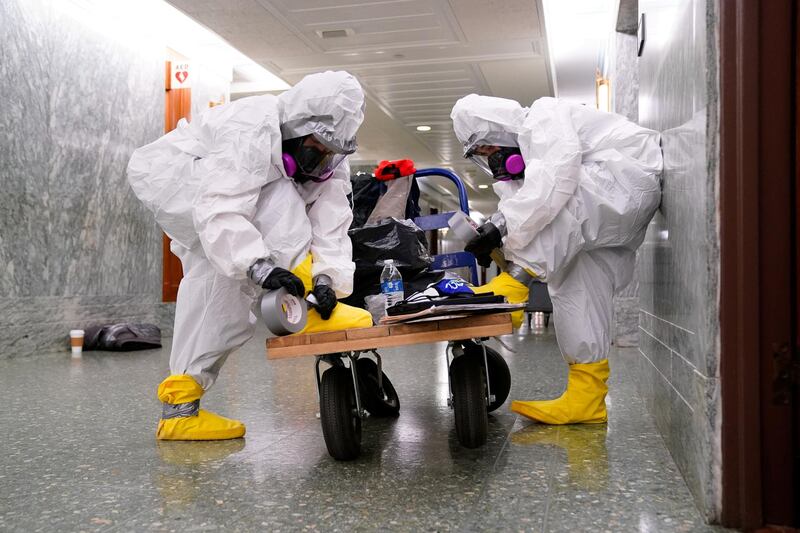 Workers seal their feet into hazmat suits as they prepare to clean the Senate Special Committee on Aging offices after a person reportedly tested positive for coronavirus. Reuters