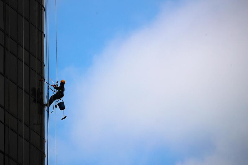 A Malaysian worker cleans the windows outside a building in Kuala Lumpur.  EPA
