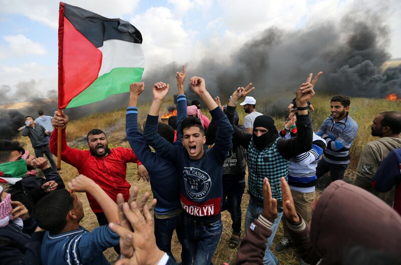 Smoke billows behind a group of Palestinians protesting near the Gaza-Israel border on Land Day, Ibraheem Abu Mustafa / Reuters