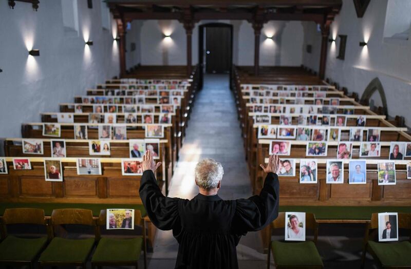 The evangelical pastor Klaus-Martin Pothmann stands in front of photos of believers who were asked to send in pictures to represent them among the pews at the St. Pankratius church in Hamm, western Germany.  AFP