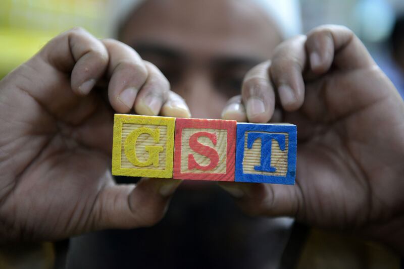 An Indian consumer goods trader shows letters GST representing Goods and Services Tax (GST) at his shop in Hyderabad. AFP