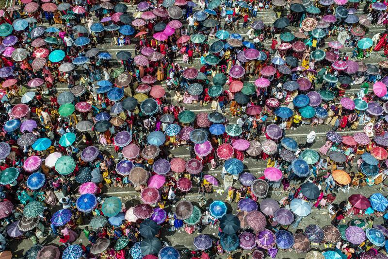 Spectators carry umbrellas during the annual Behdienkhlam festival in India. AFP
